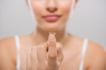 woman holding a contact lens on fingertip